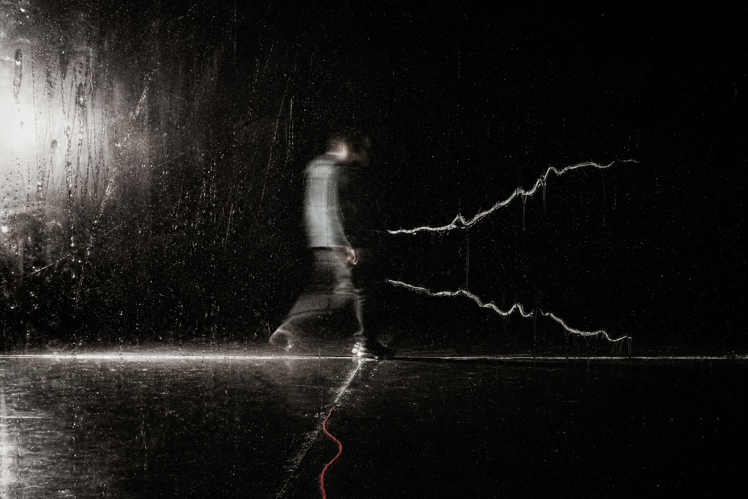 A blurred figure crossing a wet black room behind scratched glass as two hand-drawn signal lines split away.